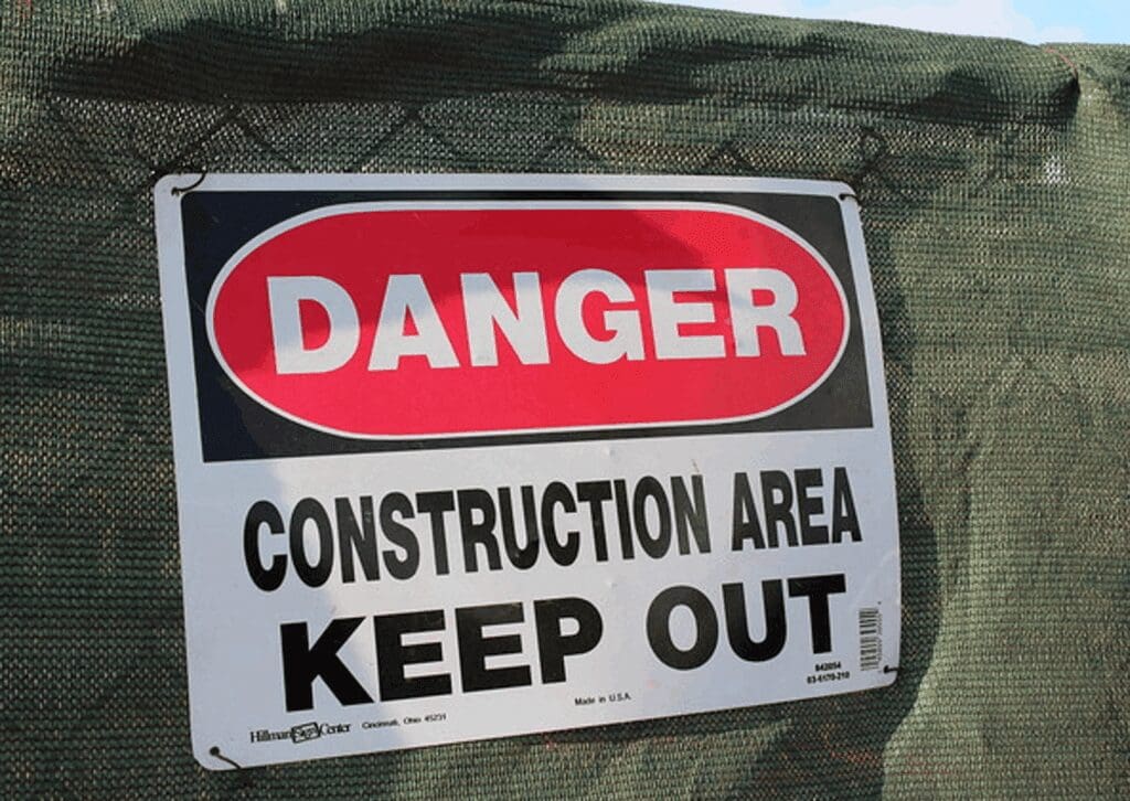 Red DANGER sign on green construction fence