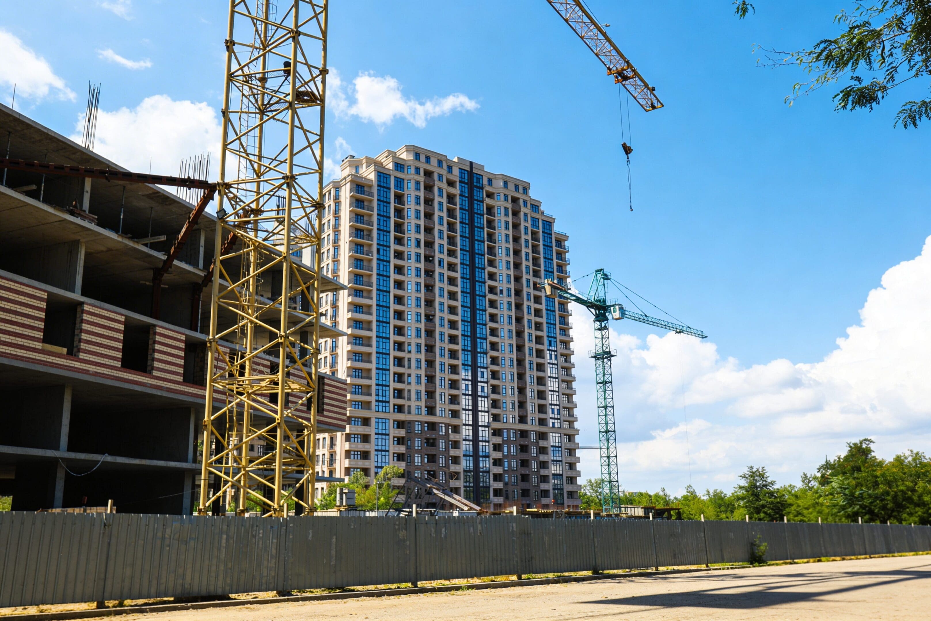 High-rise building under construction with cranes and scaffolding.