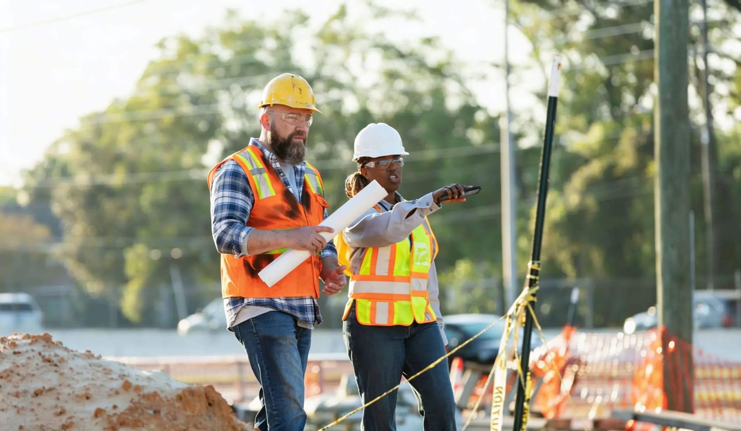Two construction workers reviewing plans at a site.