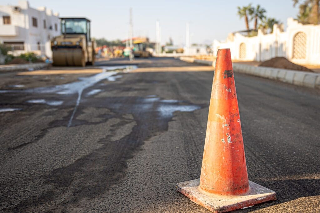 Orange traffic cone on a damaged road surface.