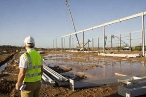 Construction worker overseeing steel framework installation at a construction site.