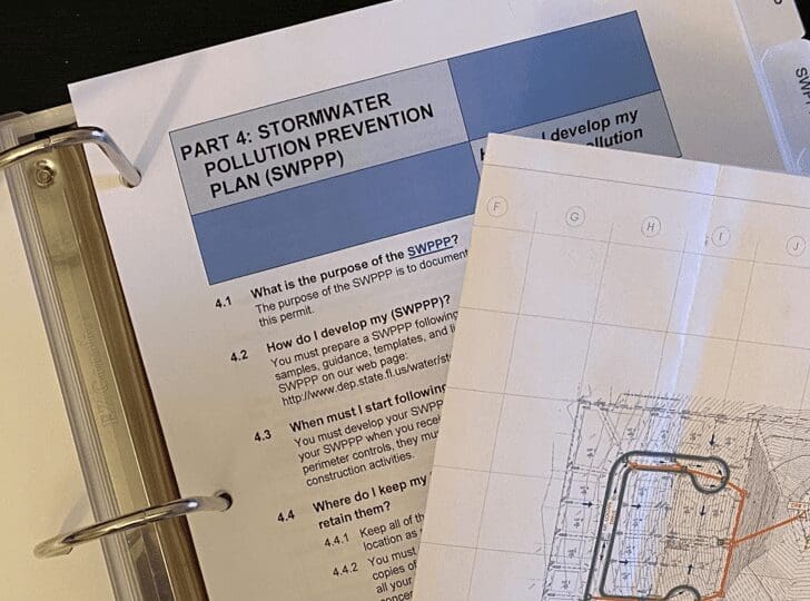 Open binder showing a Part 2 Stormwater Pollution Prevention Plan document and technical drawings.