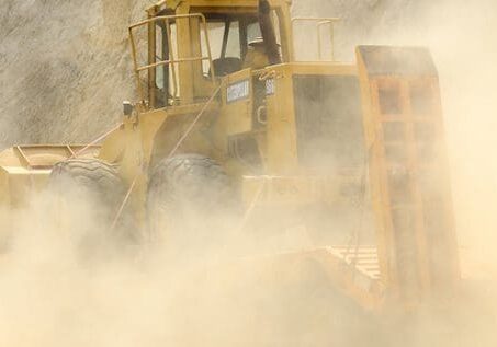 A bulldozer moving through a dusty construction site.