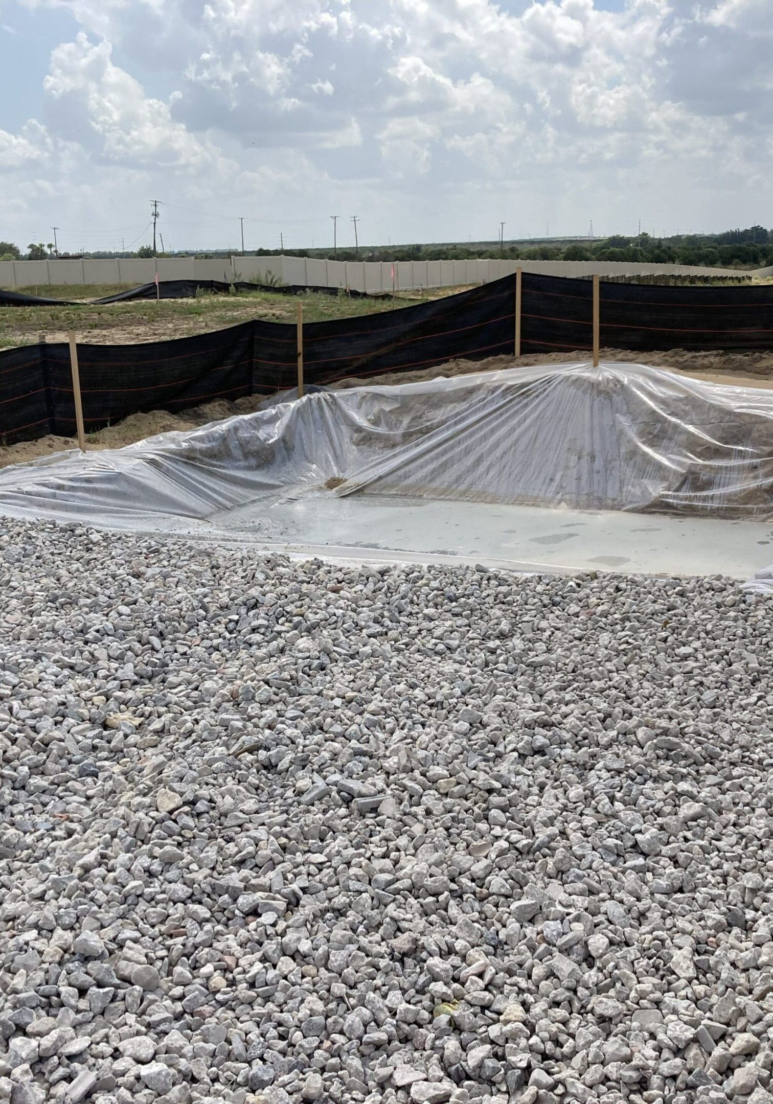 Construction site with gravel and a lined excavation pit.