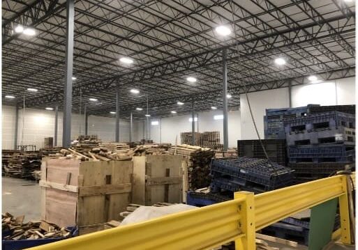 Warehouse interior with stacked boxes and pallets under bright lighting.