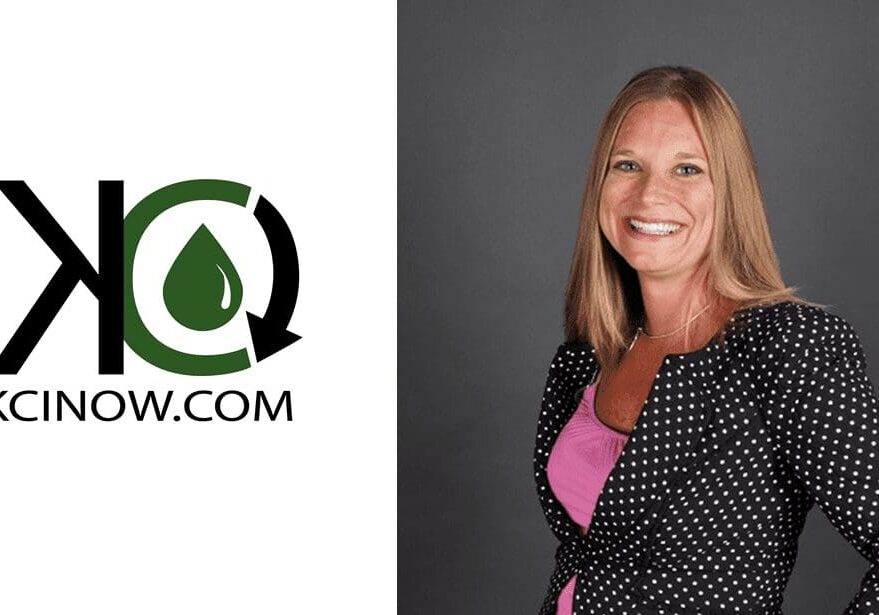 Professional woman smiling, standing against a gray background with a logo on the left.