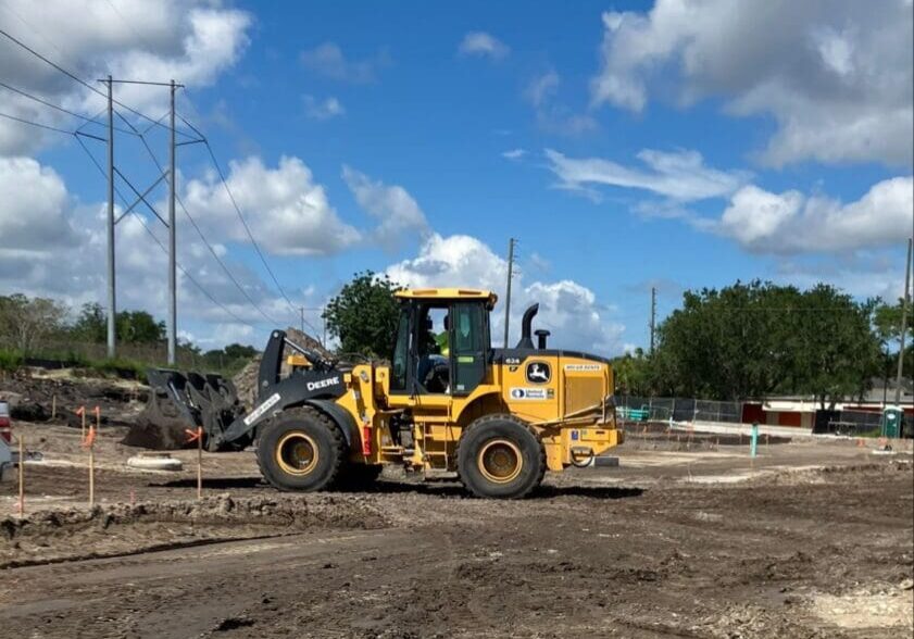 A yellow bulldozer working on a construction site under a partly cloudy sky.