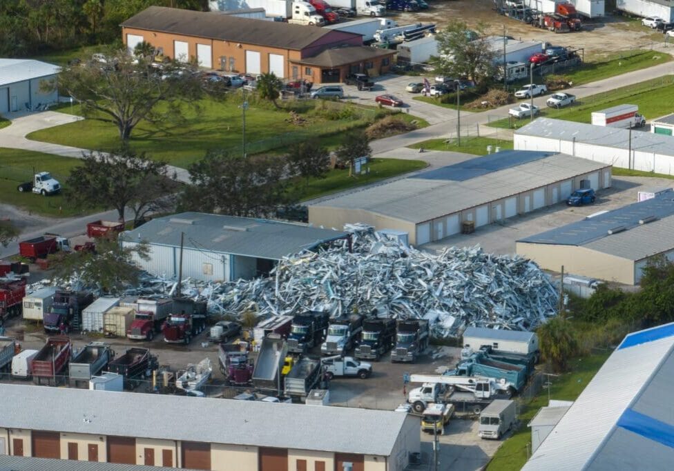 A large pile of scrap metal in an industrial yard surrounded by buildings.