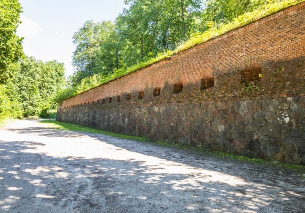 A long stone wall with small rectangular openings under a clear sky.