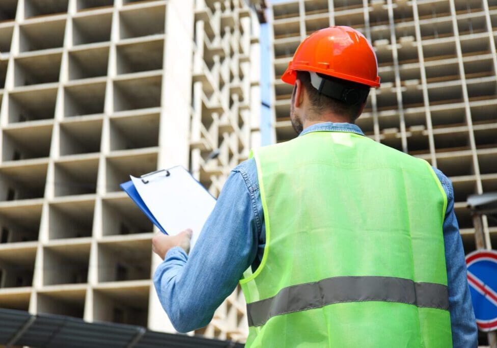 Construction worker in safety gear inspecting a building site.