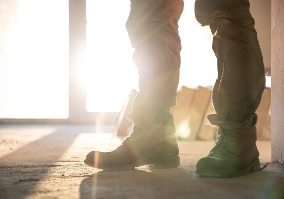 Two people walking near a bright doorway with sunlight streaming in.