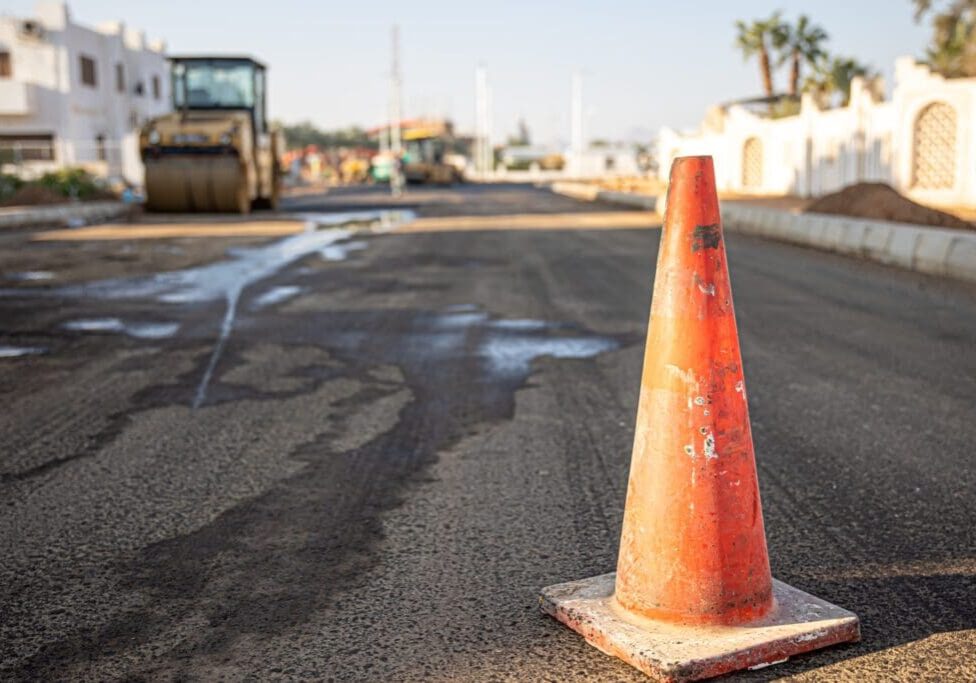 Orange traffic cone on a damaged road surface.