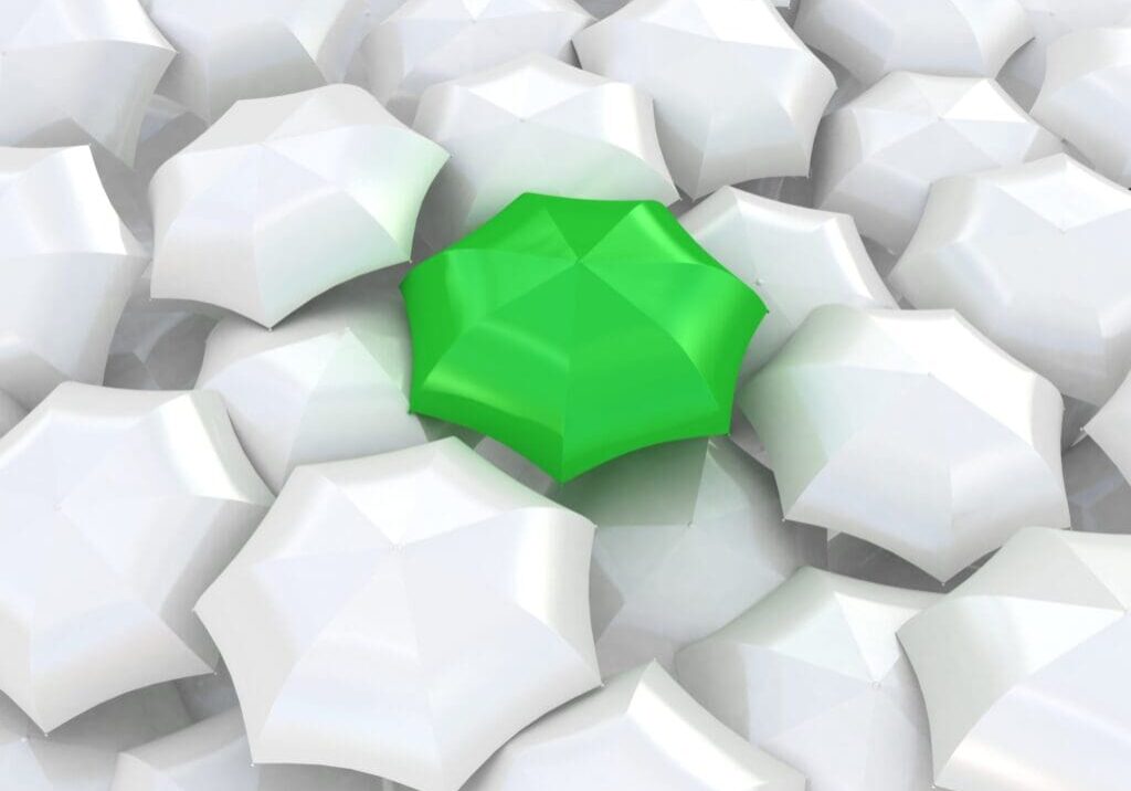 A green umbrella stands out among white umbrellas.