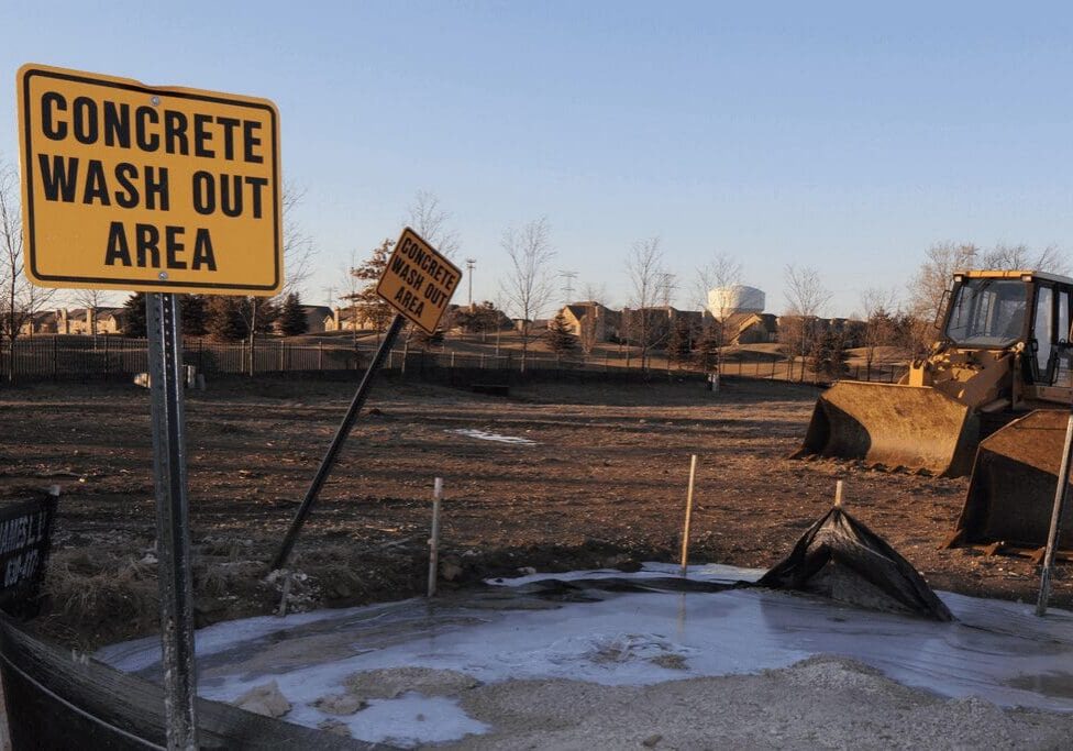 A tipped-over street sign near a construction area with barren land.