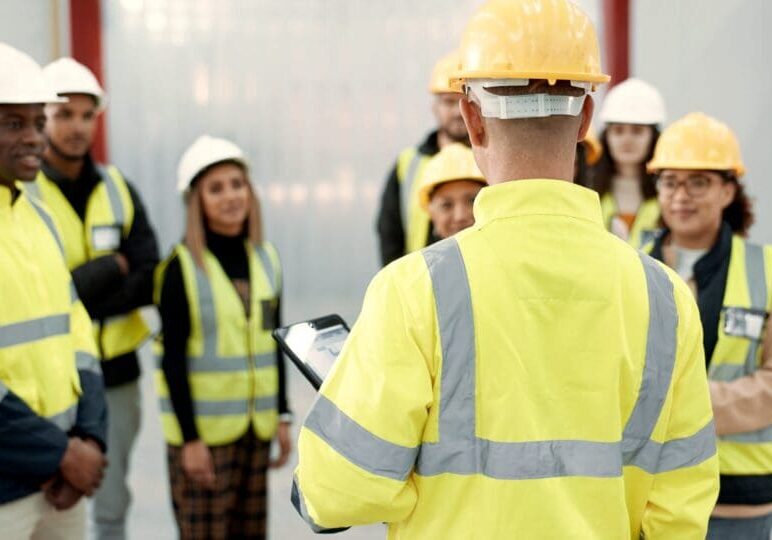 Construction worker briefing a team wearing safety gear.