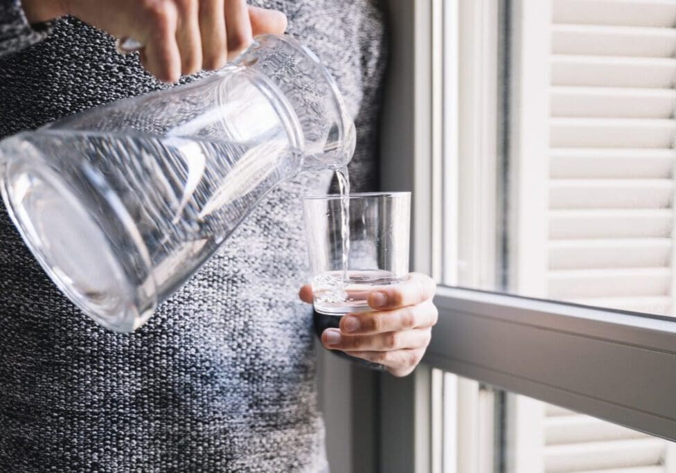 crop-man-pouring-water-near-window-scaled