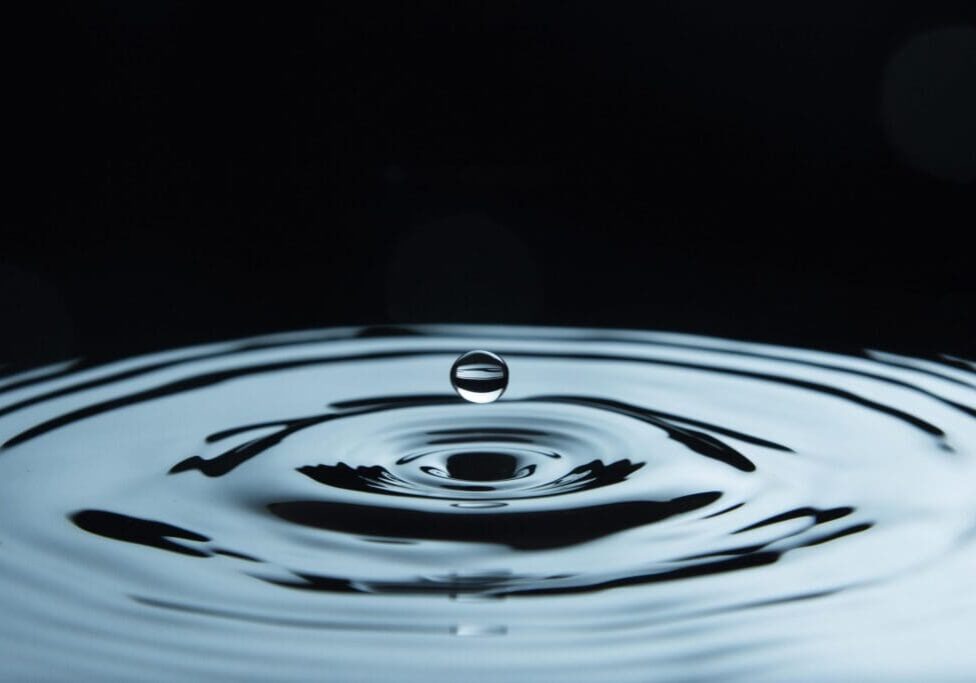 A water droplet creating ripples on a dark surface.