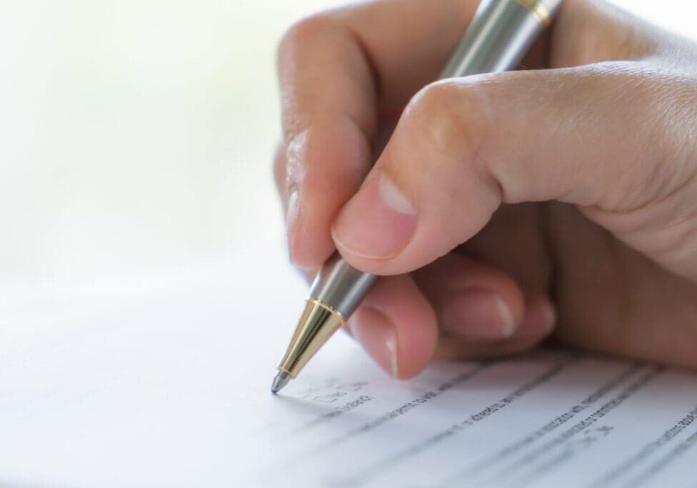 Hand holding a pen writing on paper.