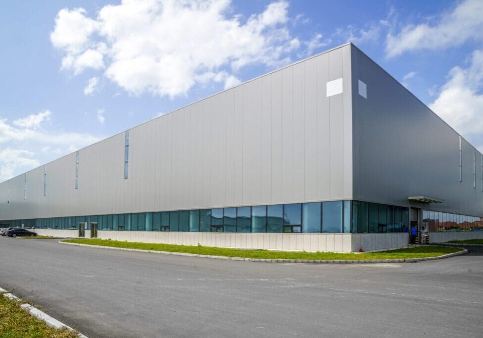 Modern industrial warehouse building under a partly cloudy sky.