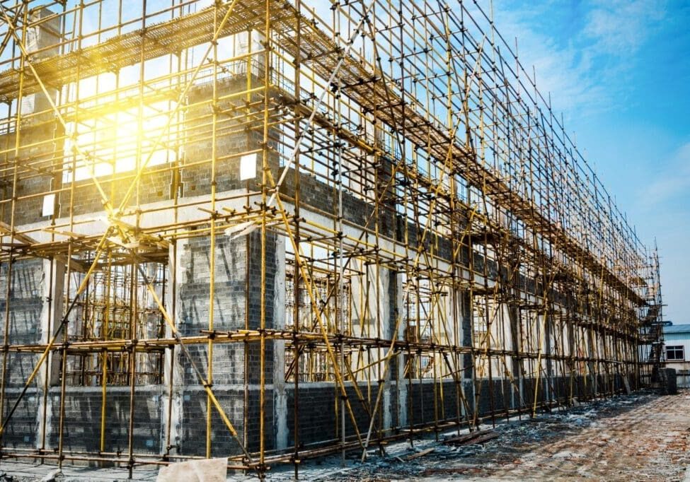Scaffolding surrounds a building under construction in sunlight.