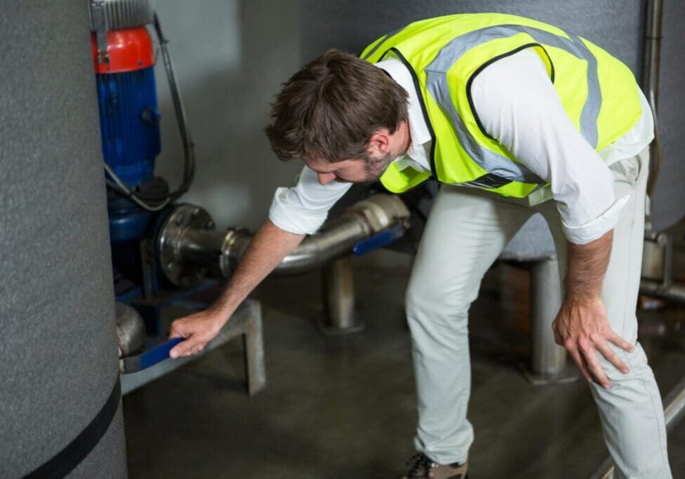 Worker inspecting machinery in a factory setting.