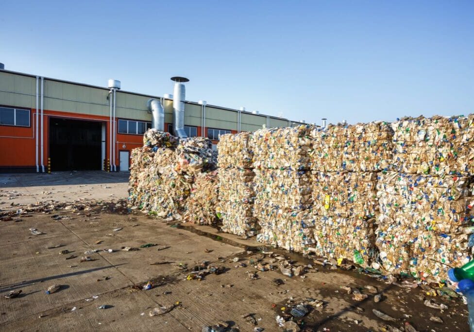 Large stacks of baled recyclable materials outside a recycling facility.