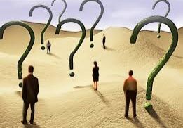 People walking among giant question marks in a desert landscape.