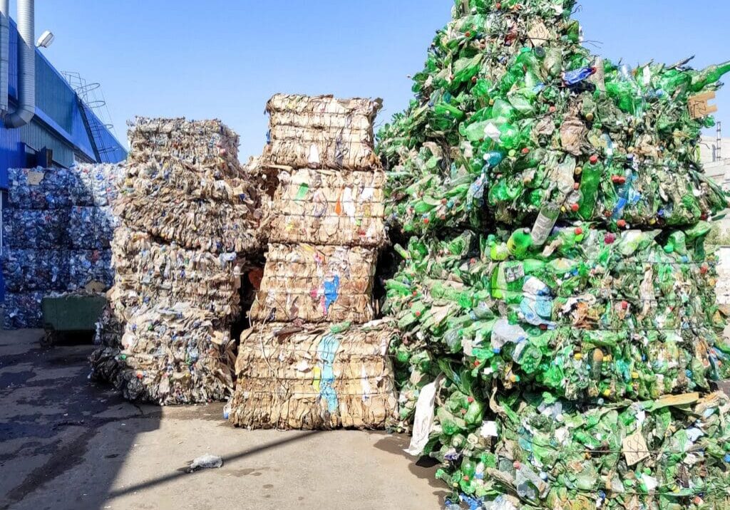 Stacks of compressed recyclable materials including plastic bottles and cardboard.