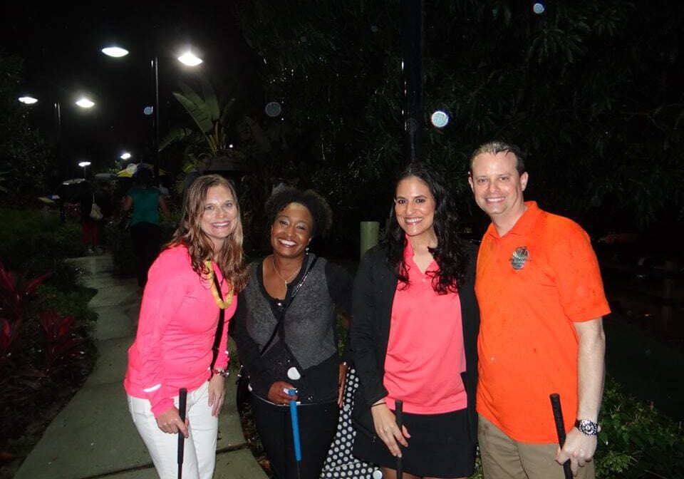 Four friends posing outdoors at night, smiling warmly.