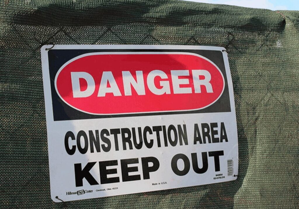 Red DANGER sign on green construction fence