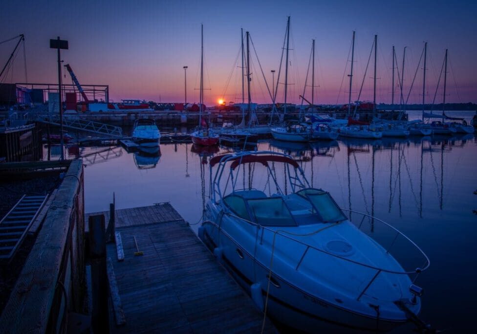 Sunset over a peaceful marina with boats docked in calm waters.