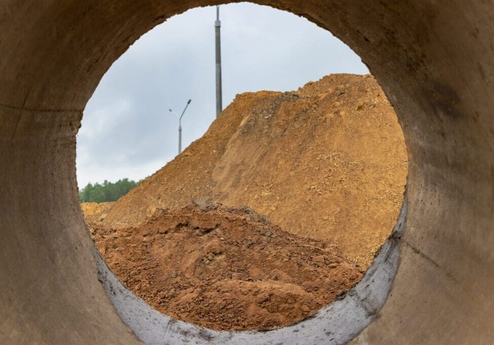 View of a dirt mound through a circular concrete pipe.