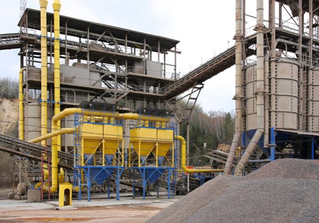 Industrial facility with large yellow tanks and conveyor belts.