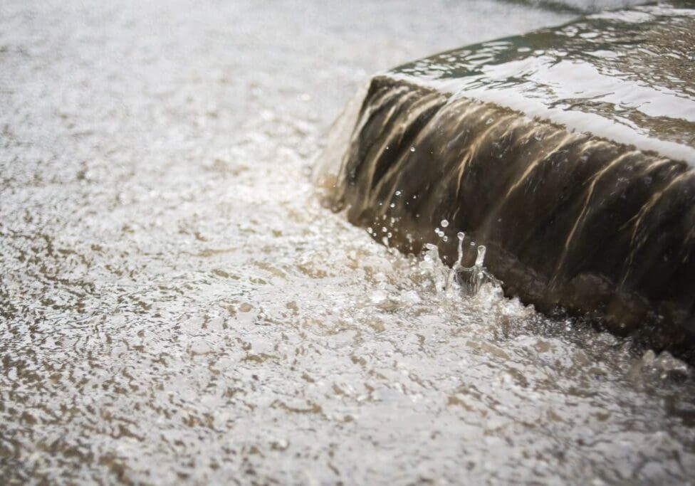 Water overflowing from a concrete edge during heavy rain.