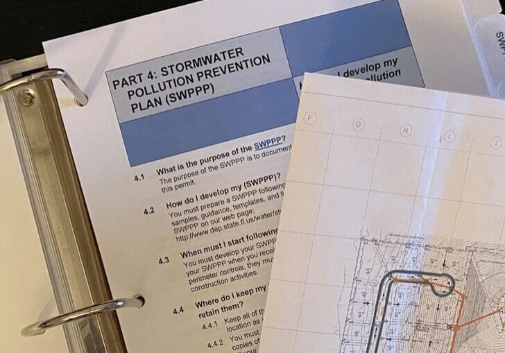 Open binder showing a Part 2 Stormwater Pollution Prevention Plan document and technical drawings.