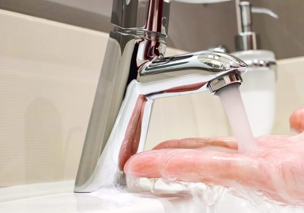 Water flowing from a modern faucet into a hand.