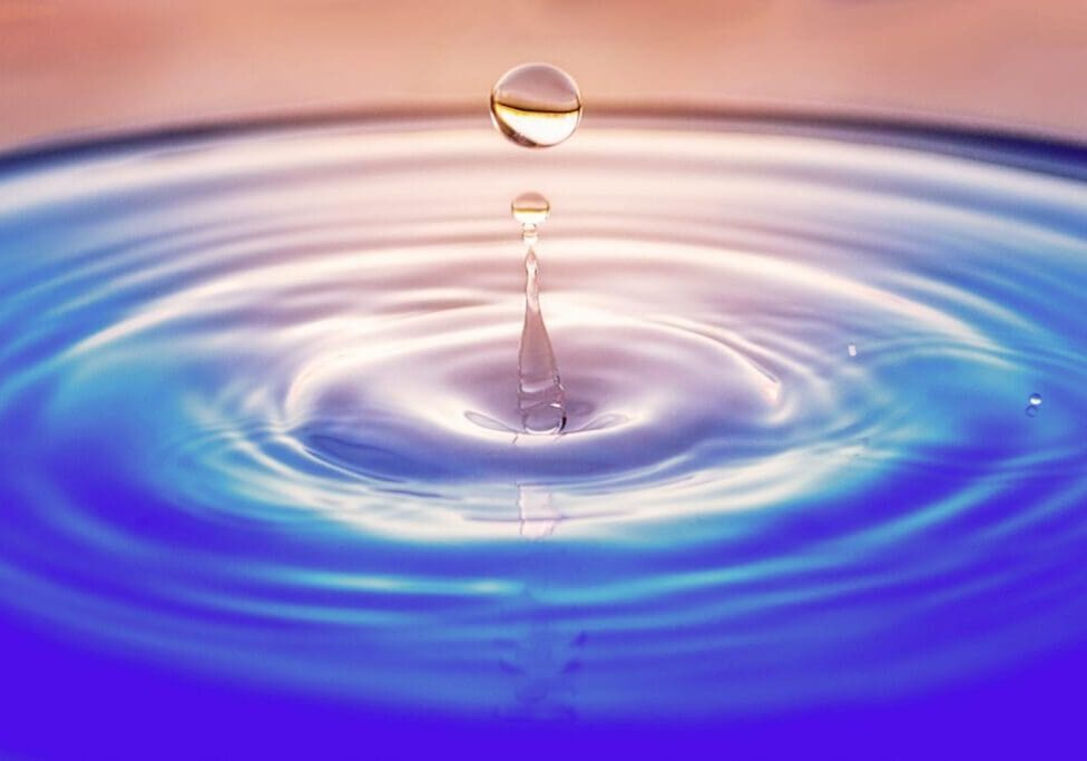 A drop of water creating ripples on a calm surface.